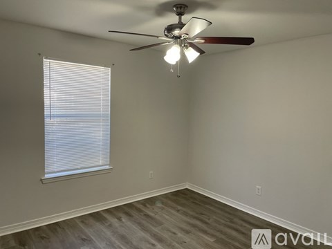 A room with a ceiling fan and a window with blinds.