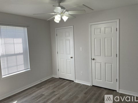A room with a ceiling fan and two doors.