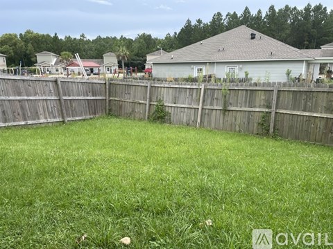 A backyard with a wooden fence and a house in the background.