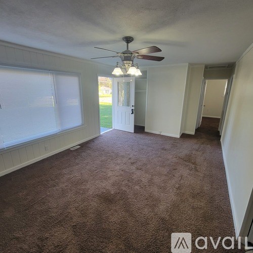 A room with a carpeted floor and a ceiling fan.