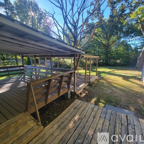 A wooden deck with a roof and railings is surrounded by trees.