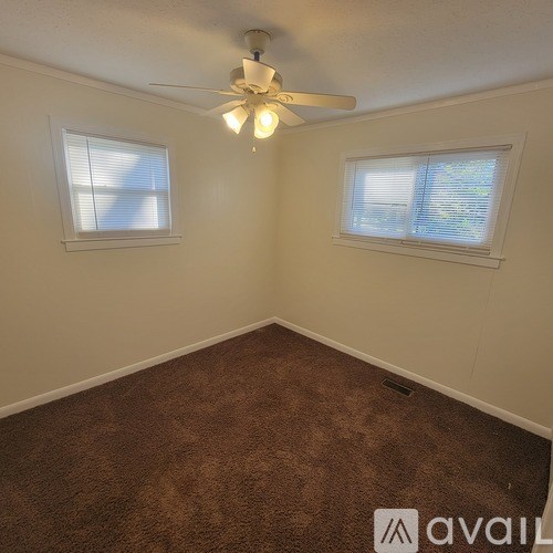 A room with a carpeted floor and a ceiling fan.