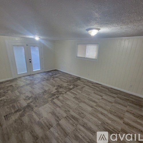 A room with wooden flooring and a window with blinds.