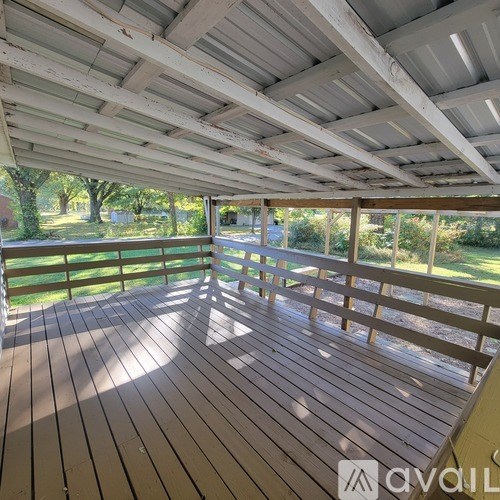 A wooden deck with a white ceiling and a railing.