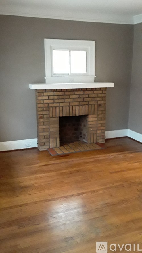 A fireplace with a white mantle and a window above it.
