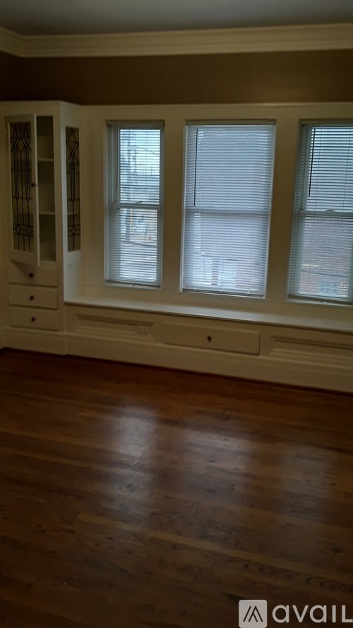 A room with a wooden floor and a window with blinds.