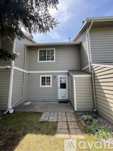 A grey house with a white door and a small porch.