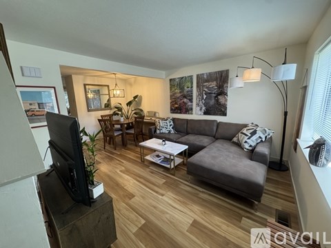 A living room with a grey couch, a wooden floor, and a television on a wooden stand.