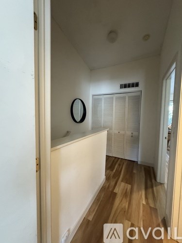 A hallway with a mirror and wooden floors.
