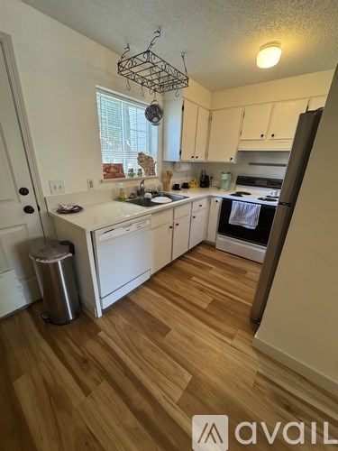 A kitchen with white appliances and wooden floors.