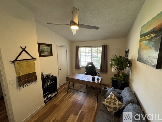 A living room with a couch, a table, a bookshelf, and a painting on the wall.