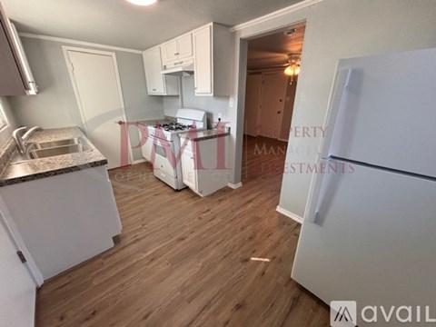 A kitchen with a white fridge, sink and cabinets.