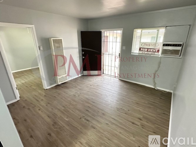 A room with wooden flooring and a sign that says "FOR RENT".