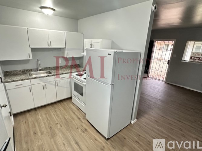 A kitchen with a refrigerator, cabinets, and a sink.