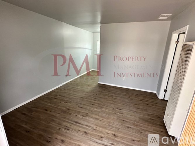 A room with wooden flooring and a wall that says "PMI Property Management Investments".