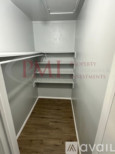 A room with wooden flooring and white walls, with a staircase leading to another level.