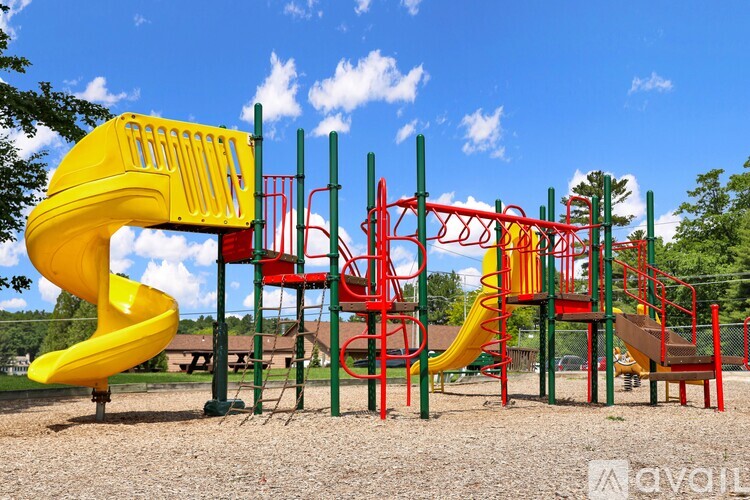 A playground with a yellow slide and red and green climbing structures.
