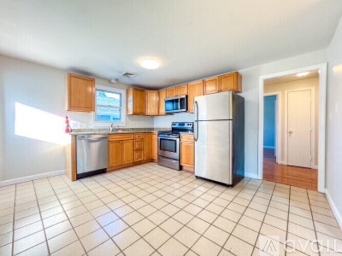 A kitchen with white tile flooring and wooden cabinets.