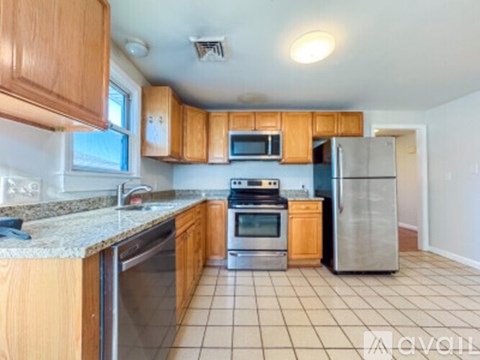 A kitchen with wooden cabinets and a tile floor.