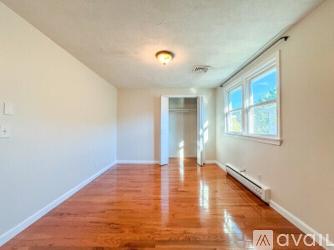 A room with wooden floors and a window on the right side.