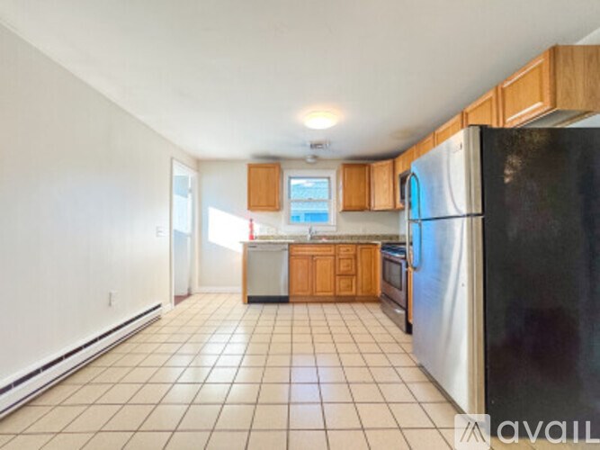 A kitchen with a black refrigerator, white walls, and wooden cabinets.