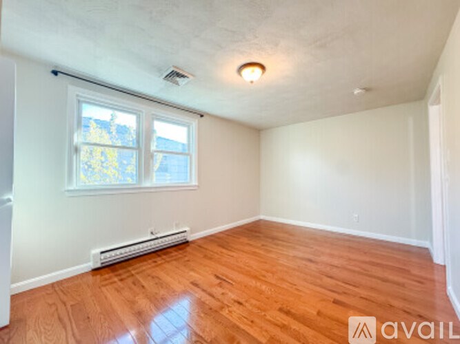 A room with wooden floors and a window with blinds.