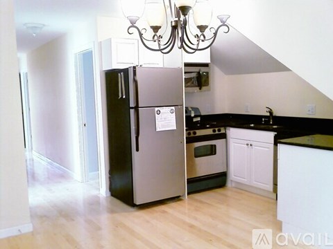 A kitchen with a black fridge and a chandelier.