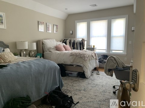 A bedroom with a bed in the center and a chair to the right.