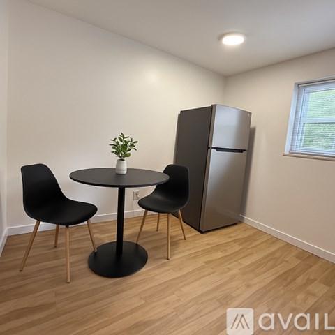 A kitchen with a table, chairs and a fridge.
