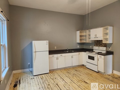 A kitchen with white appliances and wooden floors.