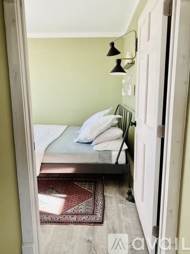 A bedroom with a bed and a rug on the floor.