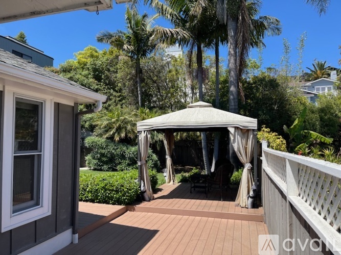 A gazebo is situated on a wooden deck with a white railing.