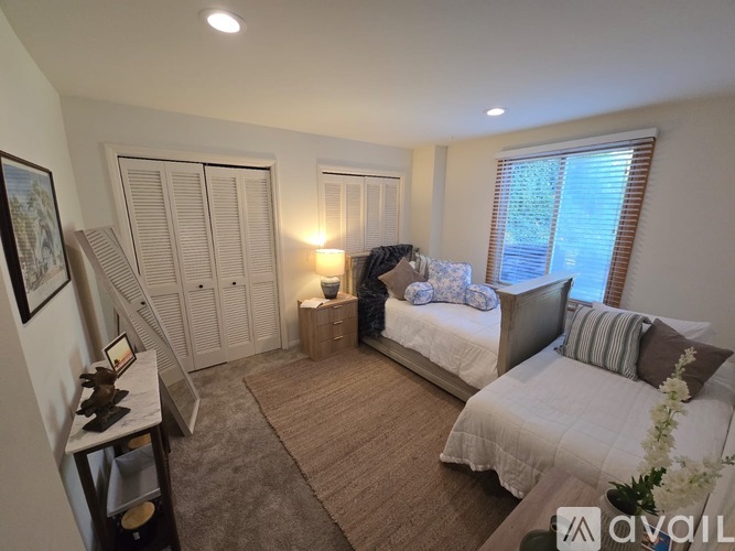 A bedroom with two beds, a nightstand, and a dresser.