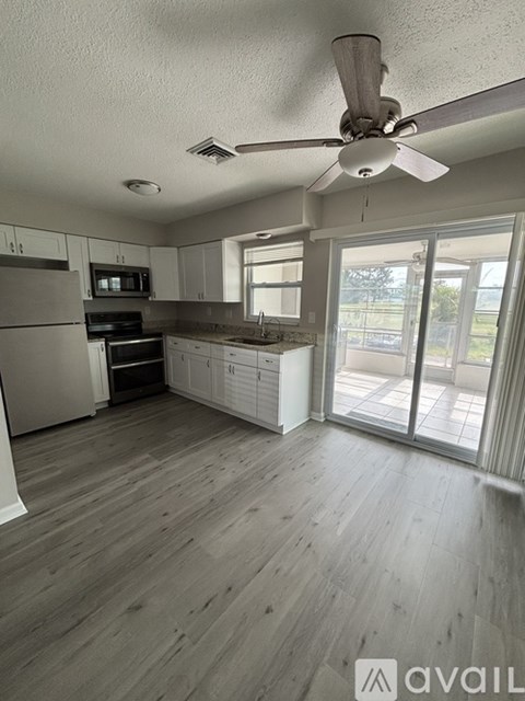 A kitchen with a fan and wooden floors.