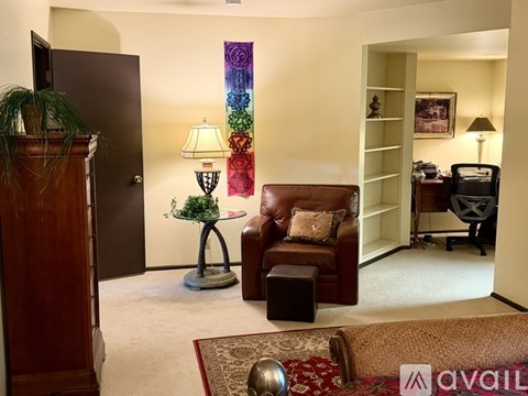 A living room with a brown leather chair and a lamp on a stand.