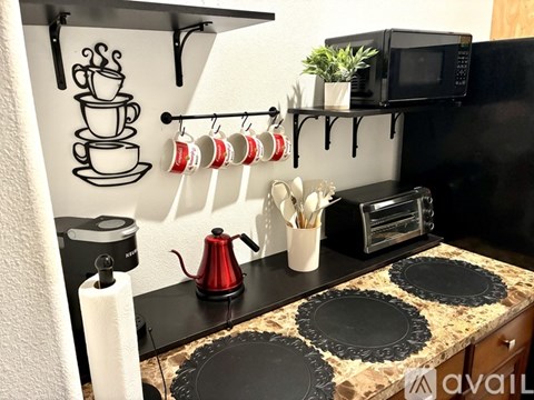 A kitchen with a black countertop and a coffee maker.