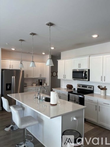 A modern kitchen with a central island and pendant lights.