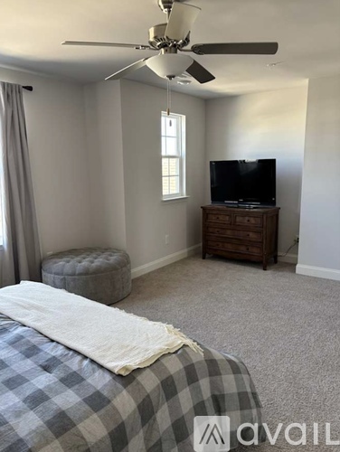 A bedroom with a bed, a television, and a window.