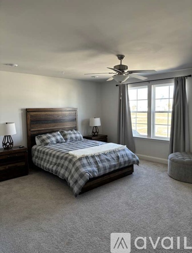 A bedroom with a bed, two lamps, and a ceiling fan.