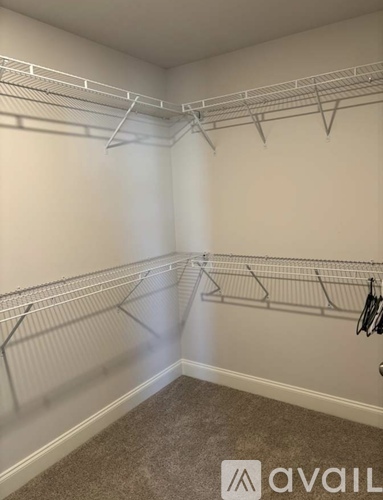 A room with white walls and a carpeted floor with a metal rack on the wall.