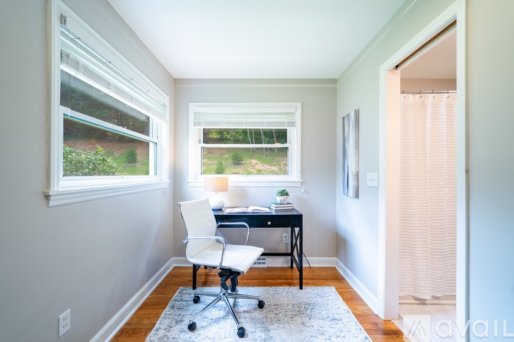 A room with a desk and chair in front of a window.