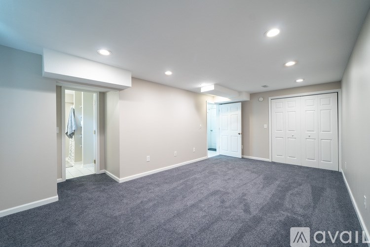 A spacious room with a grey carpet and white walls.