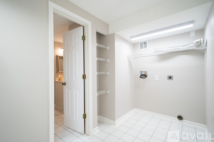 A white door is open to a room with a white tiled floor and white walls.