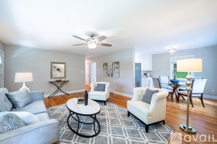 A living room with a grey couch, a white chair, and a black and white rug.