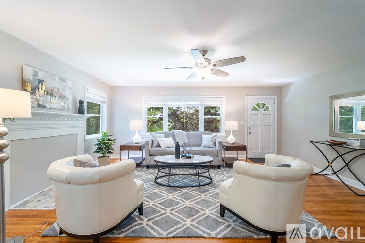 A living room with a white sofa, a black coffee table, and a ceiling fan.