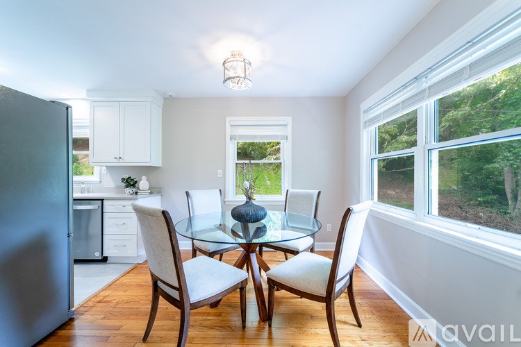 A kitchen with a glass table and chairs and a window overlooking a green area.
