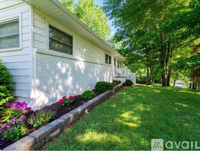 A white house with a well-kept lawn and a flower bed in front.