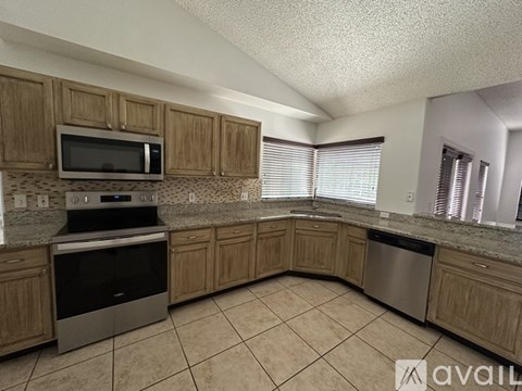 A kitchen with wooden cabinets and a tile floor.