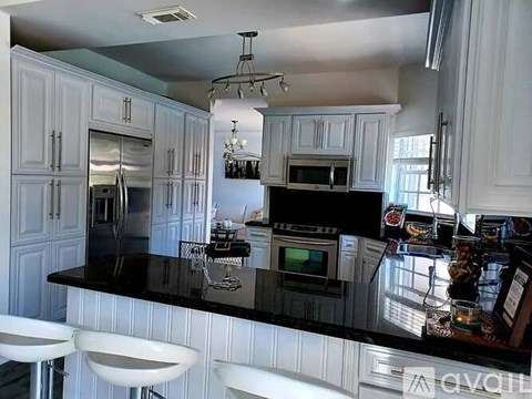 A kitchen with white cabinets and black countertops.