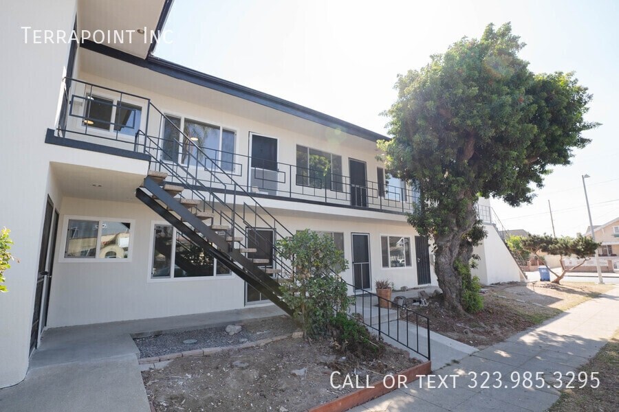 A white two-story building with a black metal staircase.